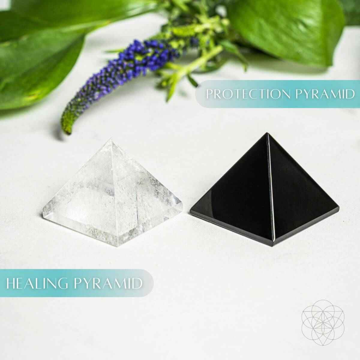 Side-by-side clear and black pyramid crystals on a white surface