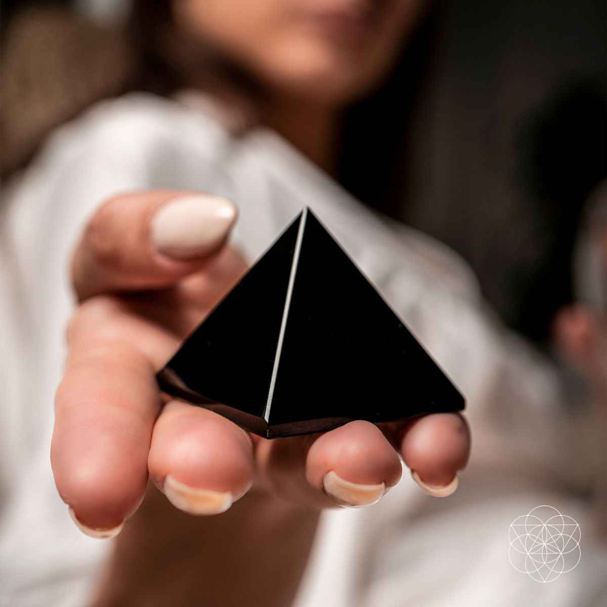 Black pyramid figurine held between fingers with pointed tip