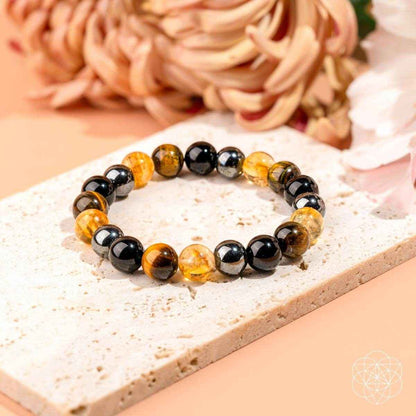 Beaded bracelet with black, amber, and tiger-eye style beads on a light stone.