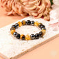 Beaded bracelet with black, amber, and tiger-eye style beads on a light stone.