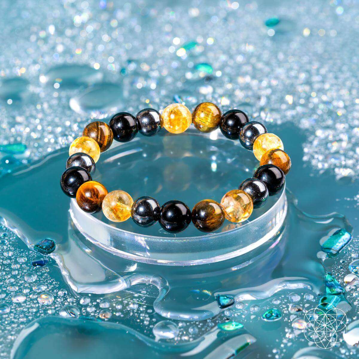 Beaded bracelet resting in water with black and amber round beads.