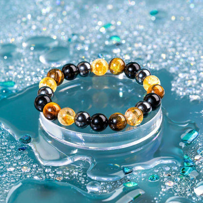 Beaded bracelet resting in water with black and amber round beads.