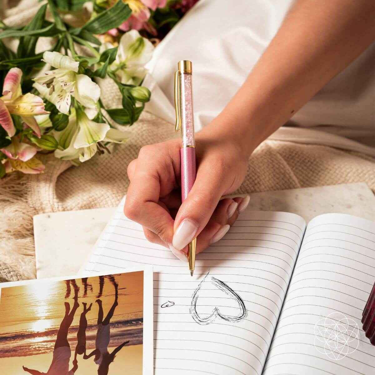Hand writing with a pink crystal self-cleansing pen on lined notebook paper.