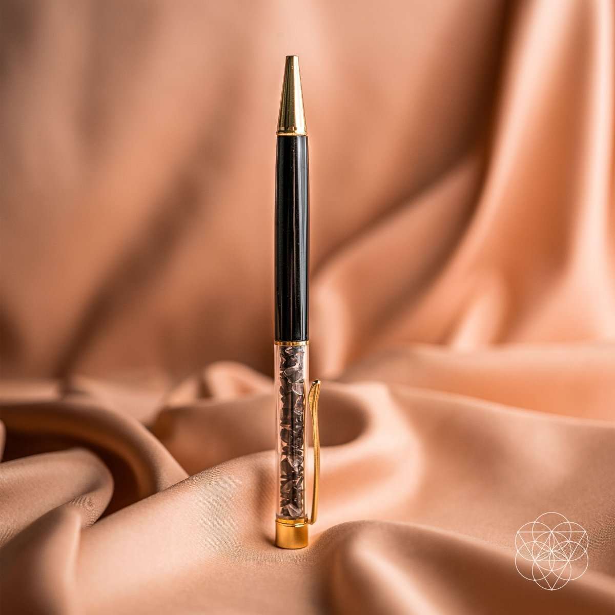 Close-up crystal self-cleansing pen with black barrel and gold top and base.