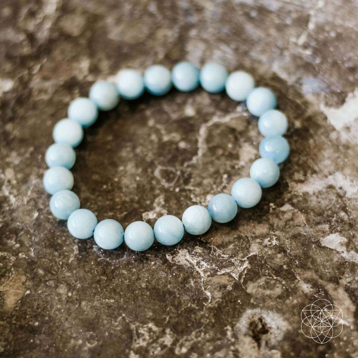 Close-up sky-blue round bead bracelet on textured rock surface.