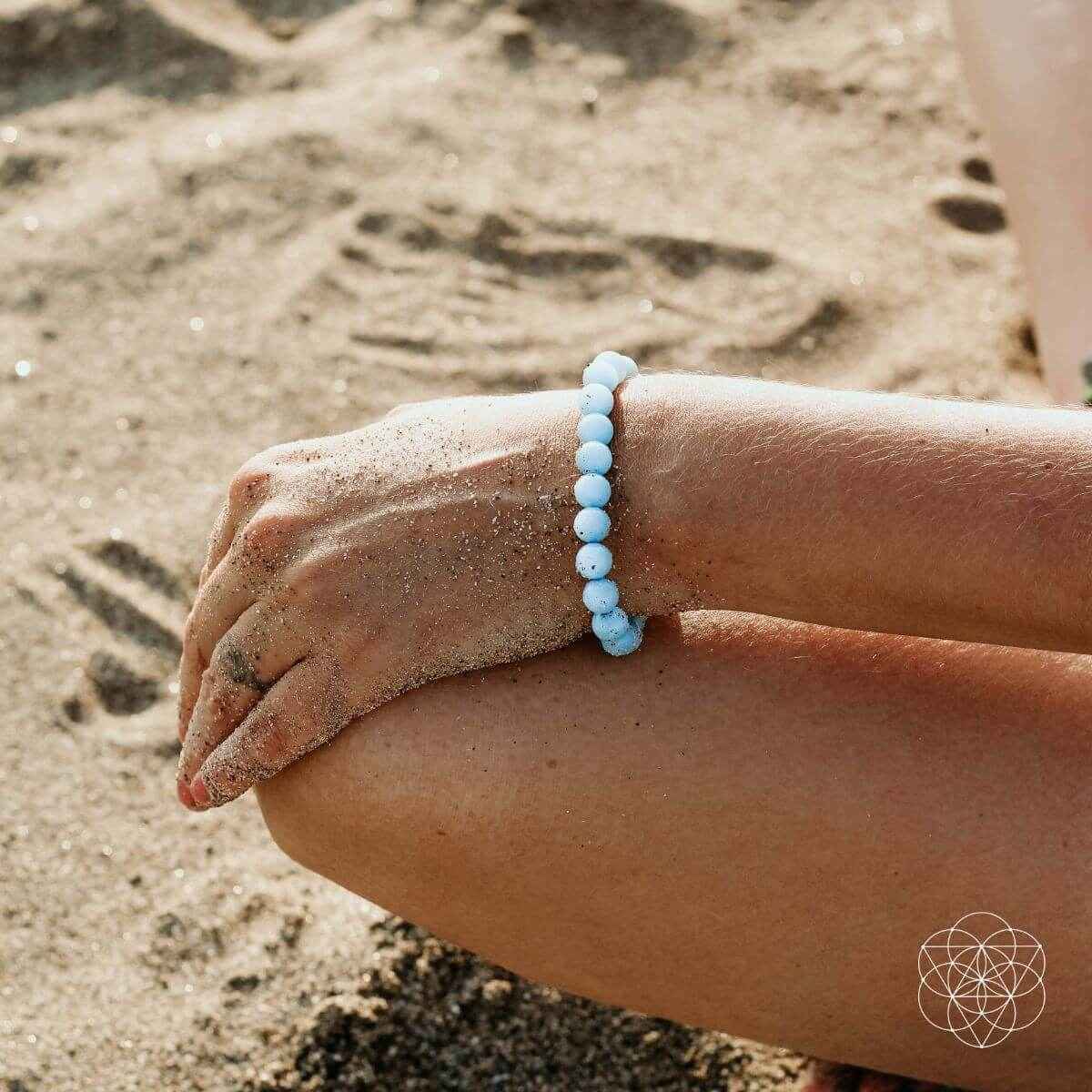 Sky-blue beaded bracelet worn on wrist, round bead design.