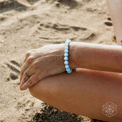 Sky-blue beaded bracelet worn on wrist, round bead design.