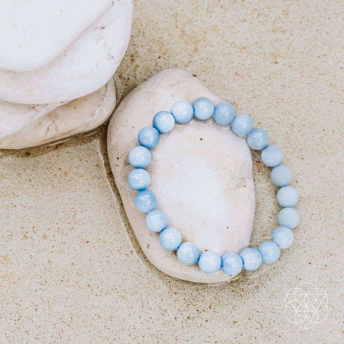Sky-blue round-bead bracelet on smooth stone, elastic loop.