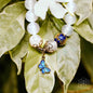 White bead spiritual growth bracelet with blue butterfly charm and gold filigree accents