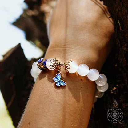 Close-up of spiritual growth bracelet with white beads and blue butterfly charm on wrist