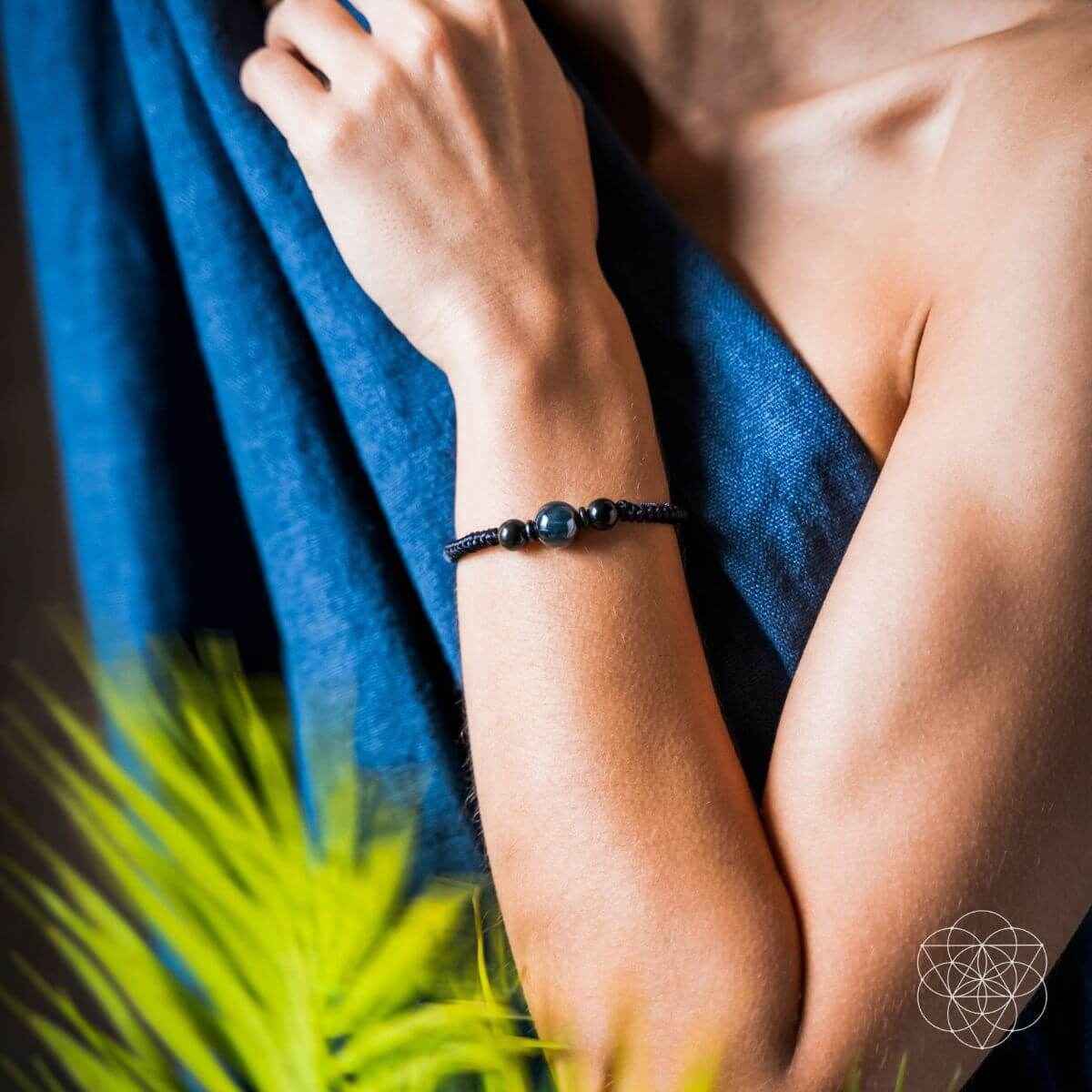Blue beaded black cord bracelet on a woman’s wrist, side view