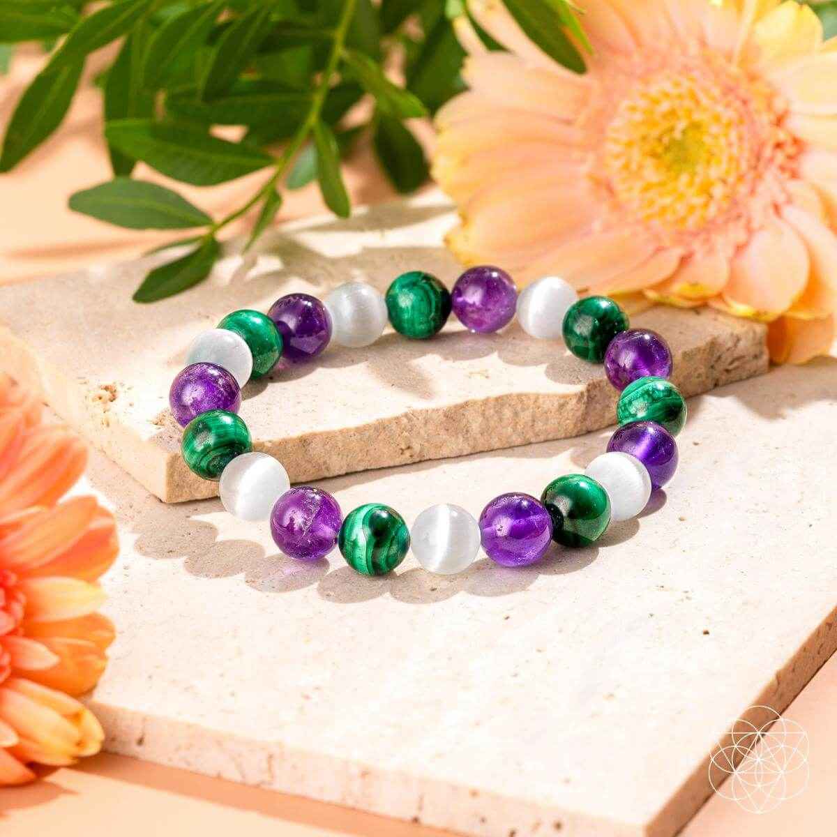 Healing bracelet with alternating green, purple, and white round beads