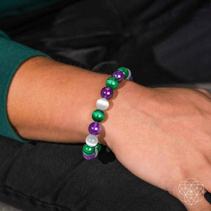 Healing bracelet on wrist featuring green, purple, and white round beads