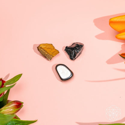 Three protection stones on pink background: gold-brown, black, and dark gray.