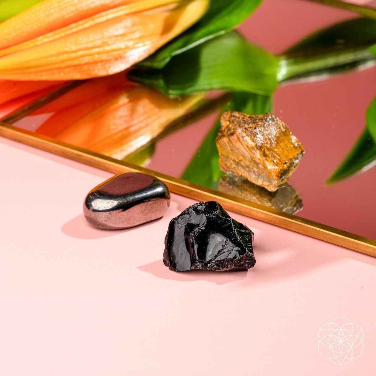 Three protection stones on display: black shard, dark gray smooth stone, and gold-brown piece.