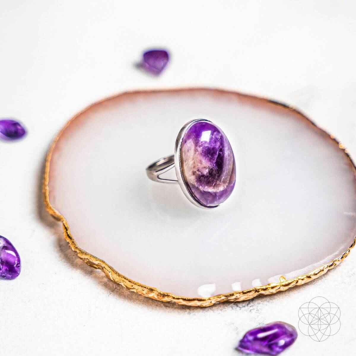 Silver ring with purple oval gemstone on white display
