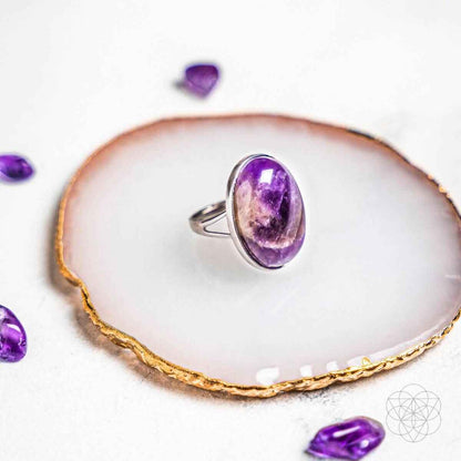 Silver ring with purple oval gemstone on white display