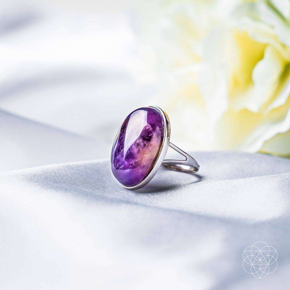 Oval purple gemstone ring with silver band, close-up