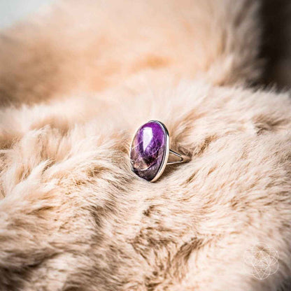 Silver ring with oval purple gemstone on light plush fur