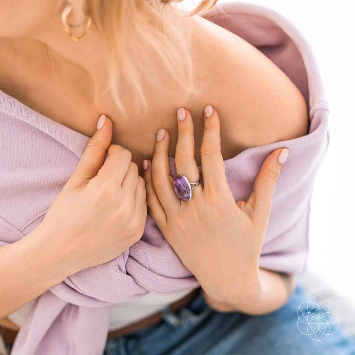 Silver ring with oval purple gemstone held near neckline