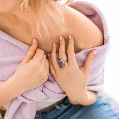 Silver ring with oval purple gemstone held near neckline