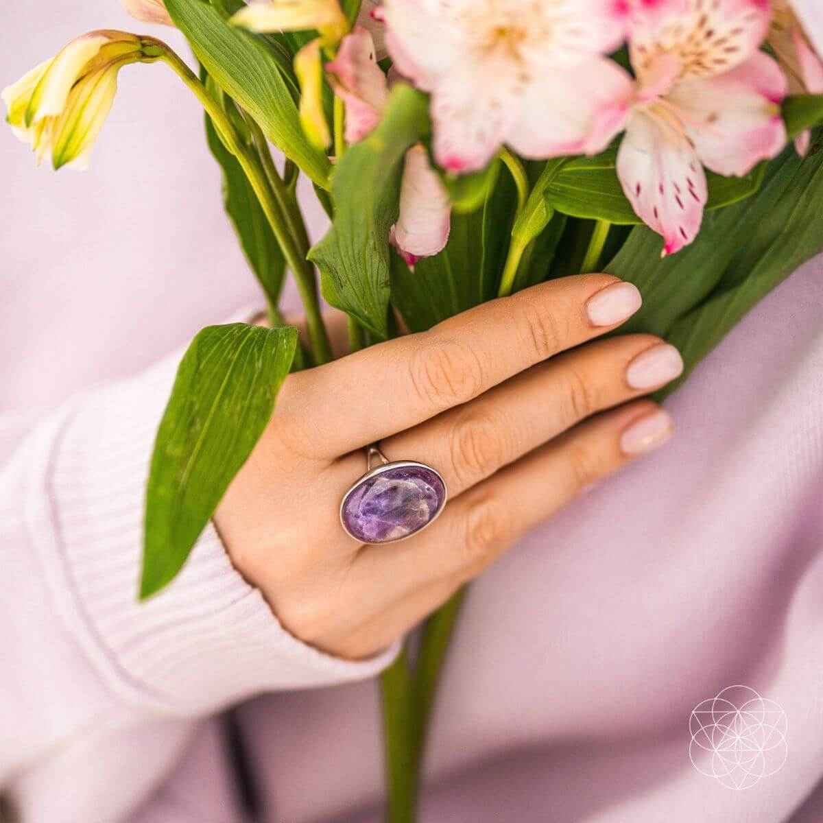 Oval purple gemstone ring on hand, silver band