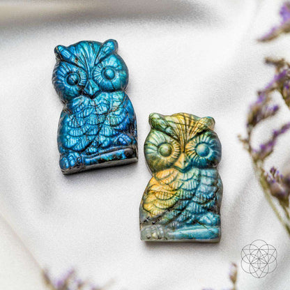Pair of labradorite owl talismans, blue and multicolor, on a fabric surface