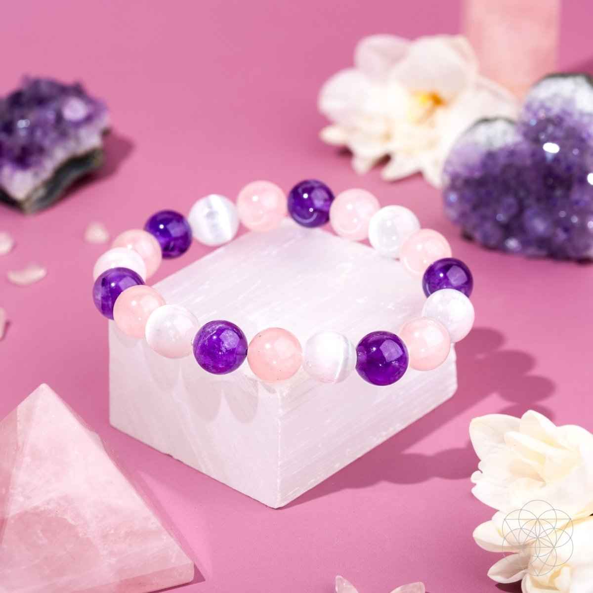 Beaded bracelet with pink, white, and purple round stones on a white block display.