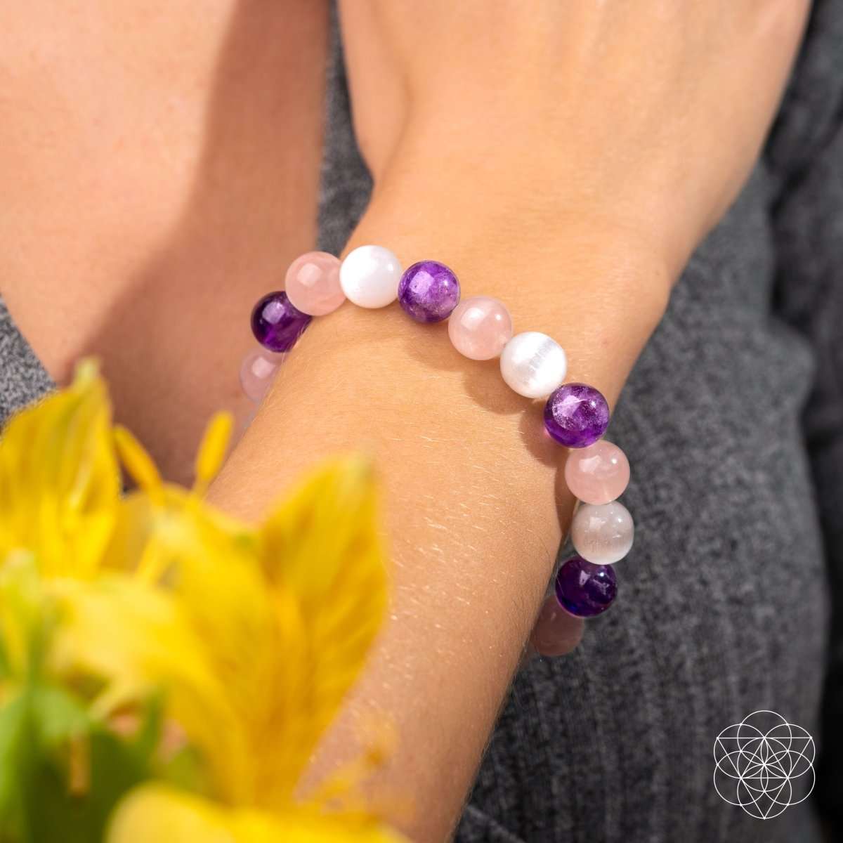 Beaded bracelet on wrist with pink and white beads and purple accent stones.