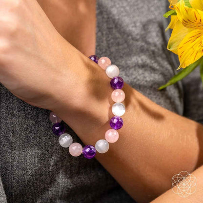 Beaded bracelet worn on wrist with alternating pink, white, and purple stones.