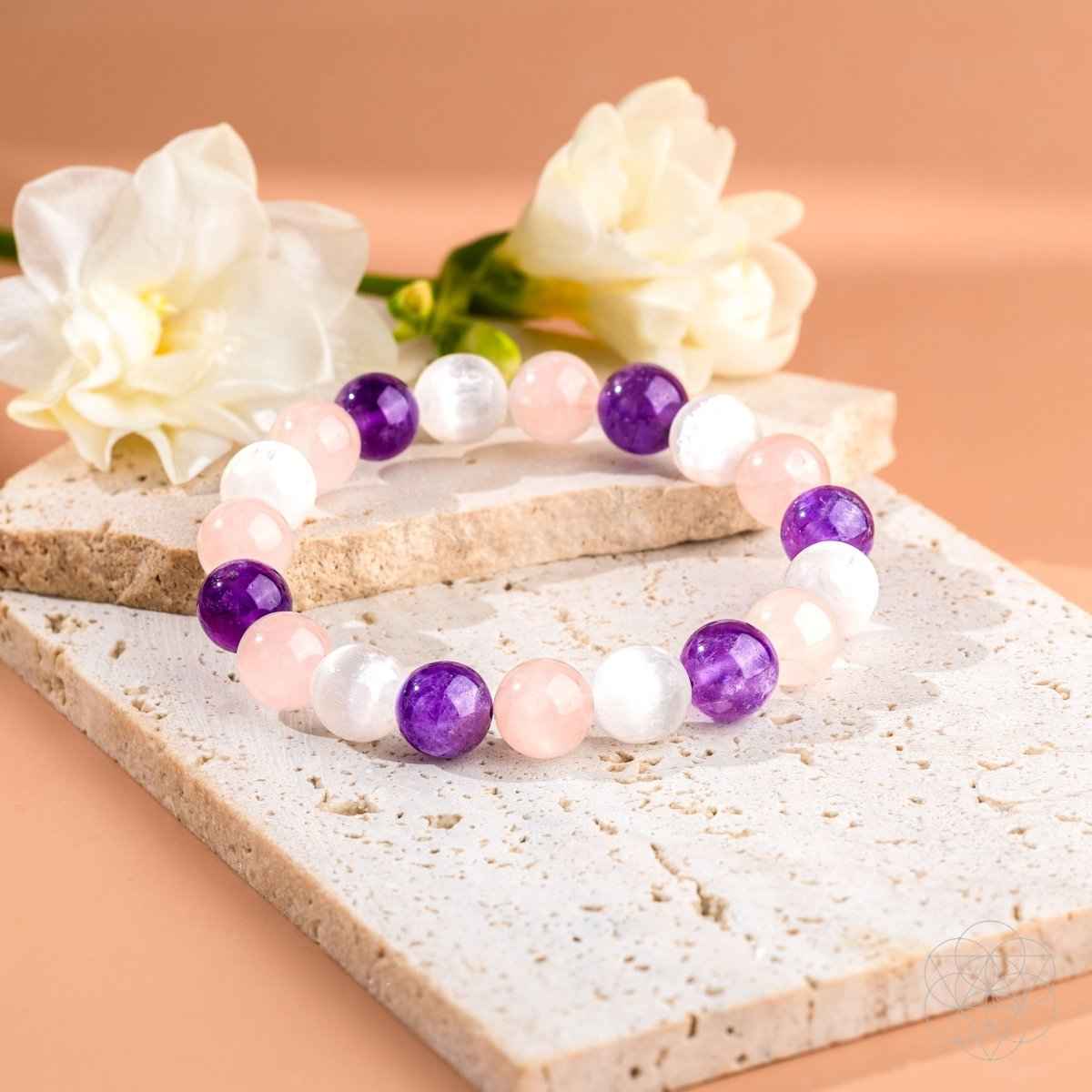 Beaded bracelet with pink, white, and purple stones on a light stone surface.