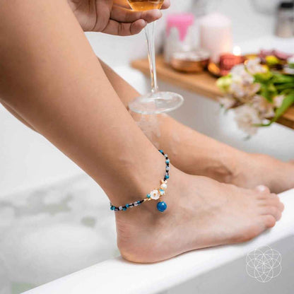 Blue beaded anklet with white flower accents and dangling blue bead