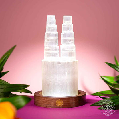 Two-tower selenite lamp with two lit crystal columns on wooden base with plants