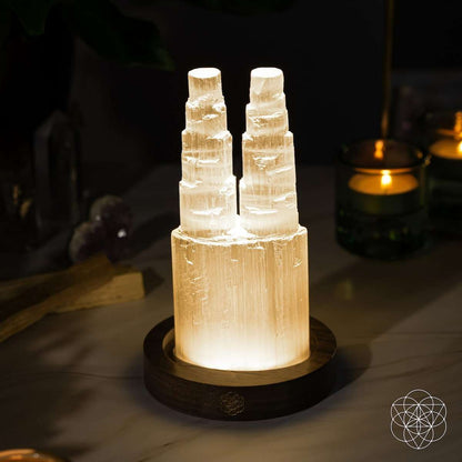 Two-tower selenite lamp with two warm golden glowing crystal columns on wooden base