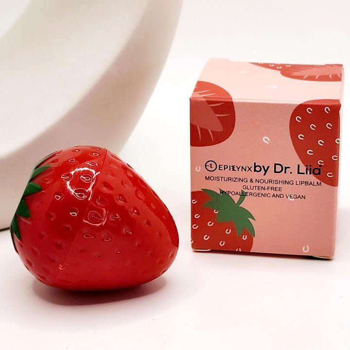 Red strawberry lip butter balm with green leaves beside product box
