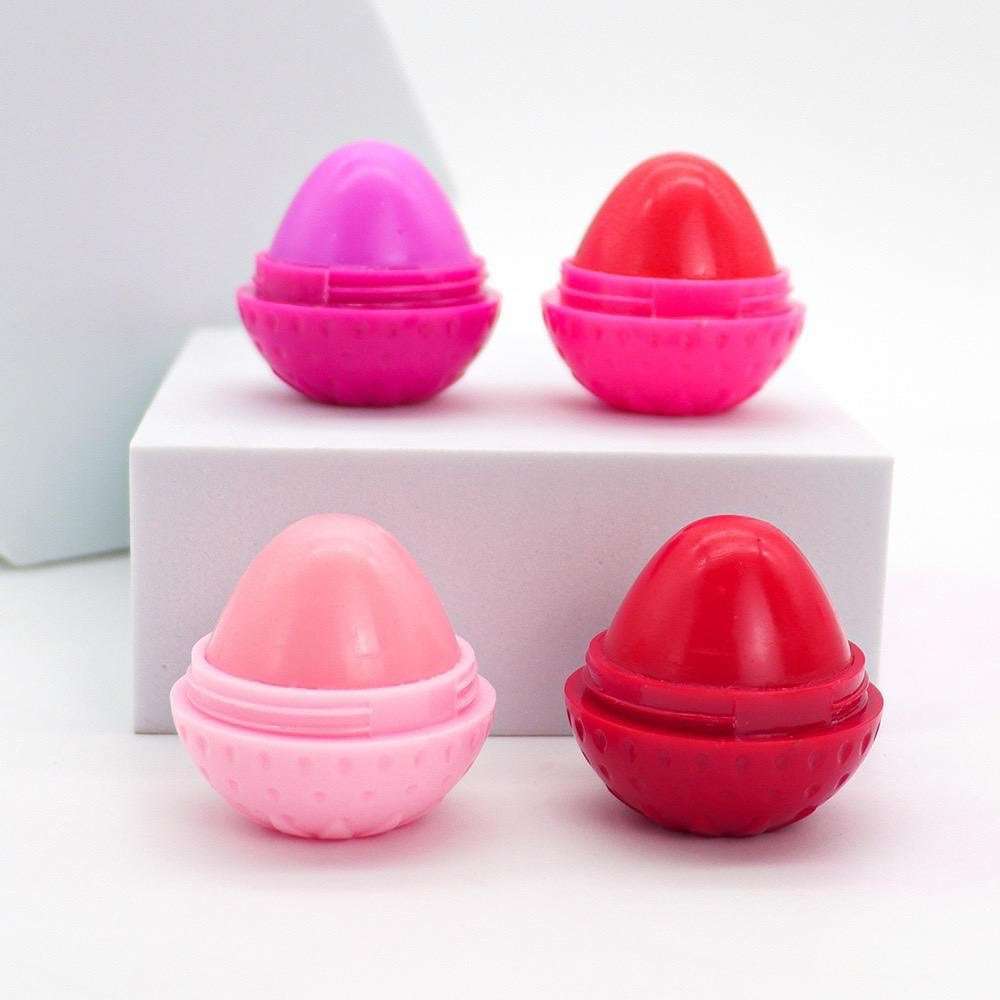Four strawberry-shaped lip butter pots in pink and red, with caps open.