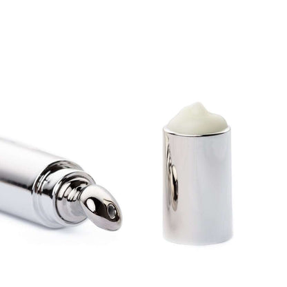 Eye cream tube and silver cap holding a small dollop of pale cream