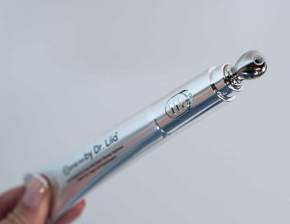 Eye cream applicator with silver roller ball and a smear of pale cream on tube