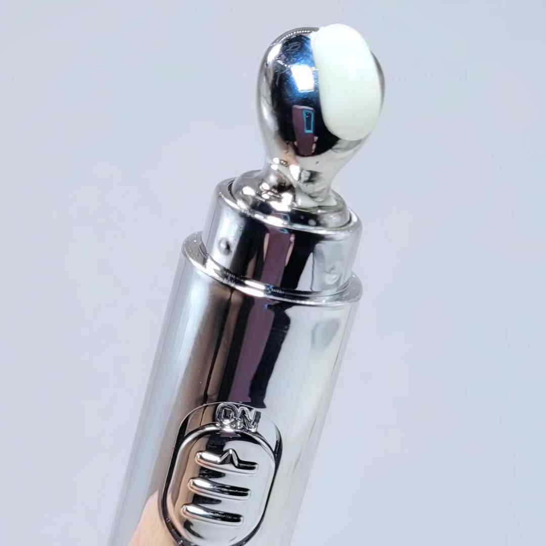 Eye cream roller applicator close-up with white cream pad on chrome cap