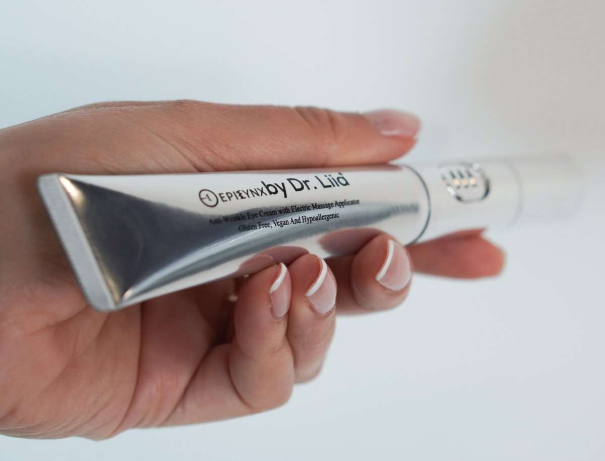 Eye cream tube in hand with silver roller tip and white cream formula