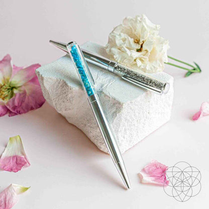 Manifestation pen set with two silver teal glitter pens on a folded cloth