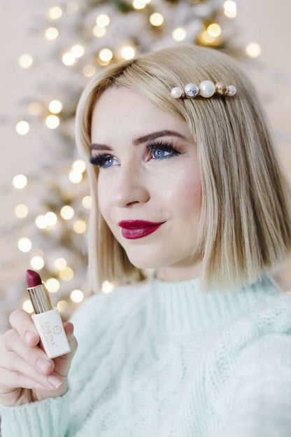 Woman holding matte lipstick, showing gold tube and red lip color