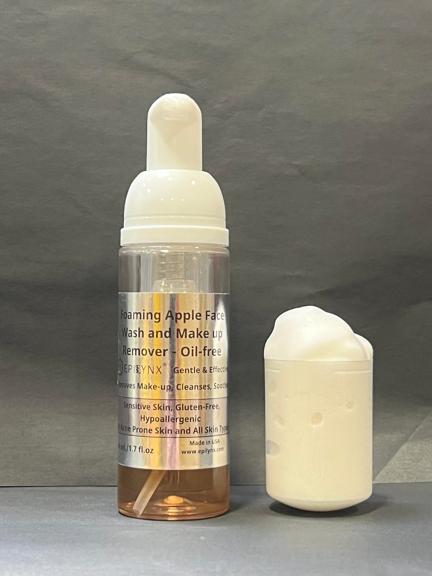 Foaming facial cleanser bottle with white pump and foam beside it