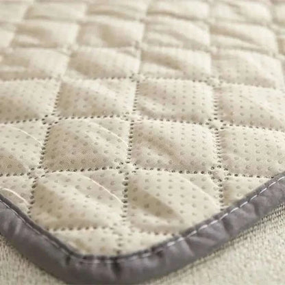 Pet bed cover, cream textured quilt with gray edge trim close-up.
