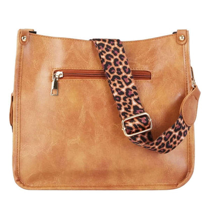 Tan leather crossbody bag with leopard-print strap and front zip pocket
