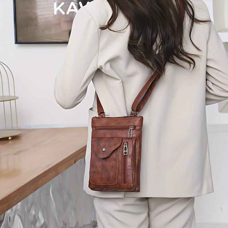 Brown leather crossbody bag with flap closure, front pocket, and long strap