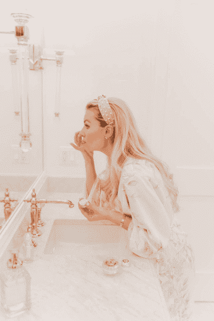 Woman applying skincare by a bathroom sink with EpiLynx products nearby