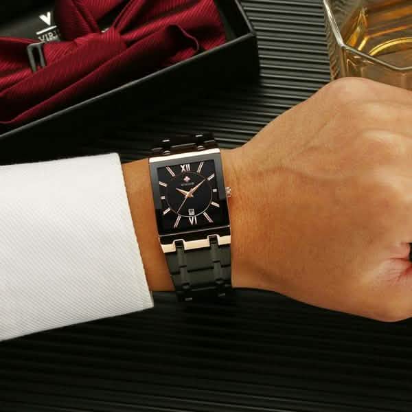 Men’s square date watch on wrist with black dial and black metal link band