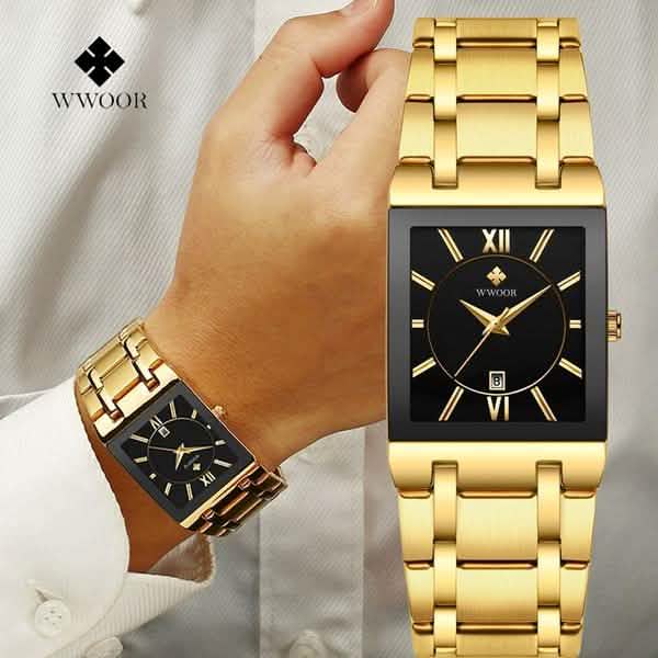 Men’s square date watch on wrist with gold dial, gold metal links, and black details